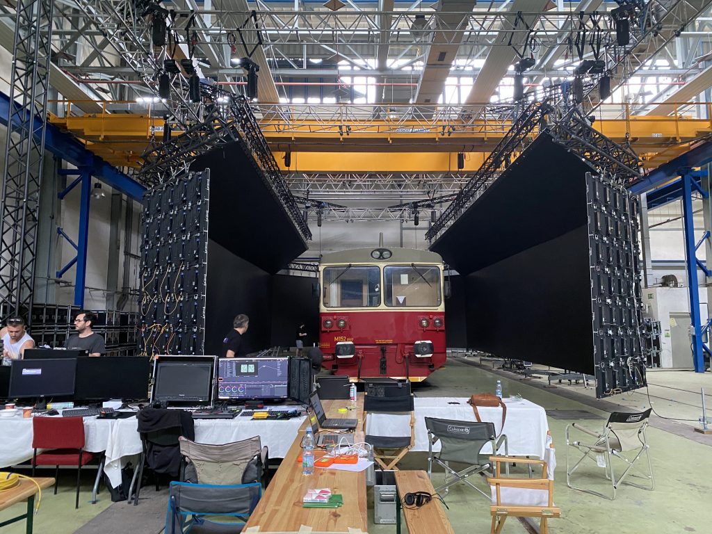 A red train car sits on set with LED walls to the left and right.